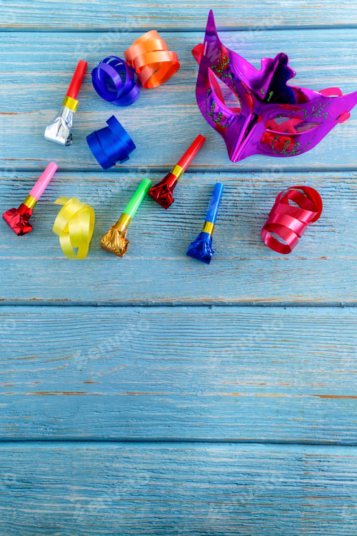 Preview: Carnival mask and party blowers on blue wood
