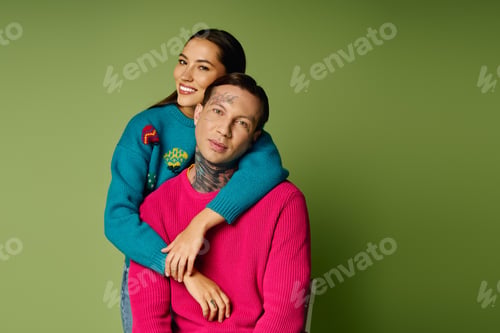Preview: A young couple poses together in colorful sweaters against a green backdrop in a cozy setting