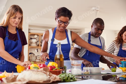 Preview: Male And Female Adult Students Preparing Ingredients For Dish In Kitchen Cookery Class