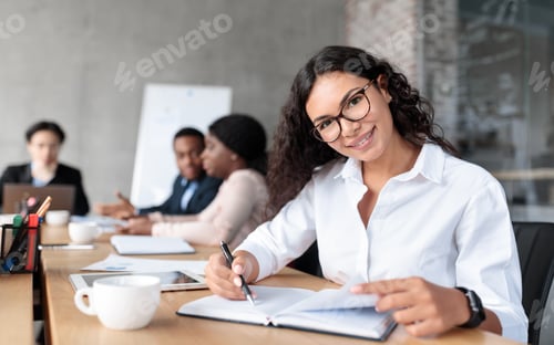 Preview: Cheerful Latin Businesswoman At Corporate Meeting Posing Sitting In Office