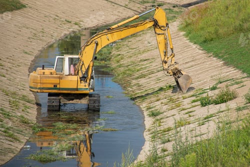Preview: Close-up shot of a yellow crane cleaning a narrow reservoir from herbs