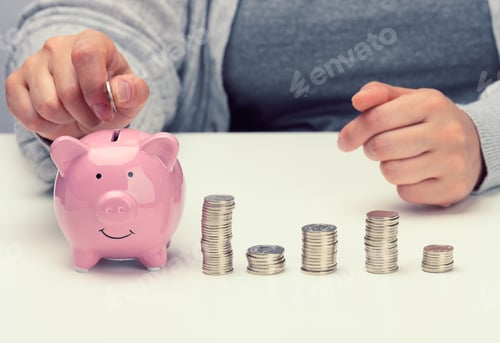 Preview: Female hand throws a coin into a pink piggy bank on a white table