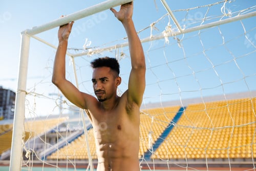Vista previa: Young shirtless African American sportsman near football goal after game at city stadium