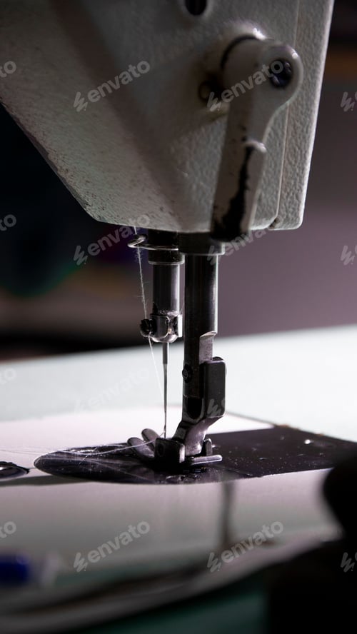 Preview: Closeup shot of a vintage sewing machine stitching a piece of fabric on a wooden table