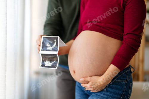 Preview: Woman and her boyfriend holding up an image of her sonogram of the baby. New family, love, baby