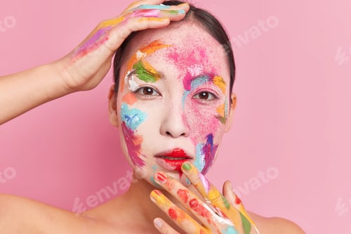 Preview: Studio shot of serious tender Asian woman with combed dark hair painted face has creative colorful m