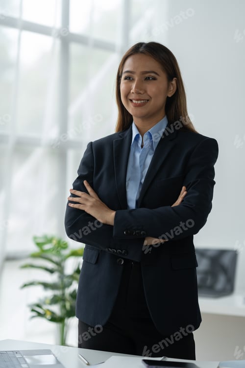 Preview: Cheerful and confident Asian businesswoman standing with arms crossed smiling happily at camera in m