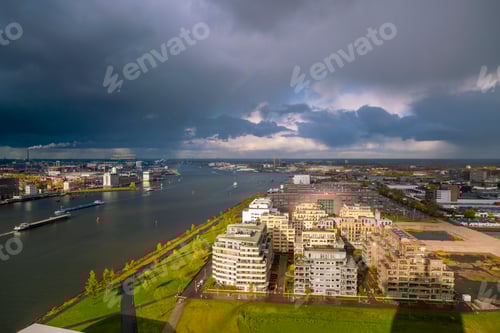 Preview: Dramatic cityscape under a stormy sky with a rainbow arching over the horizon