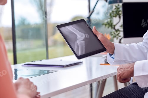 Preview: Close Up Of Doctor In Office Showing Mature Female Patient X-Ray Or Scan On Digital Tablet