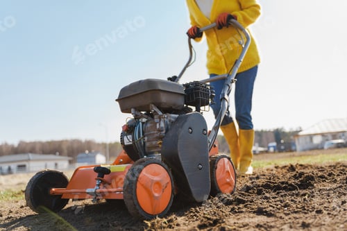 Preview: Woman villager is using aerator machine to scarification and aeration of lawn or meadow