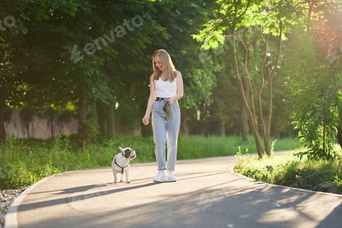 Preview: Smiling woman walking with french bulldog in park