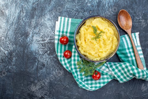Preview: Top view of mashed potatoes served with dill wooden spoon fresh tomatoes on green stripped towel on