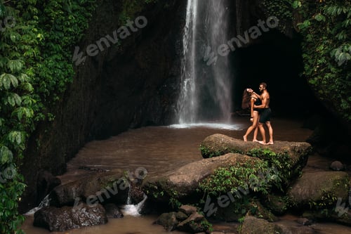 Preview: Lovers at the waterfall. Couple admiring a beautiful waterfall in Indonesia