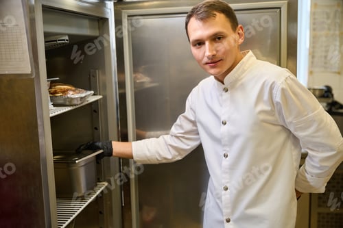 Preview: Cook in uniform puts a container of food in refrigerator