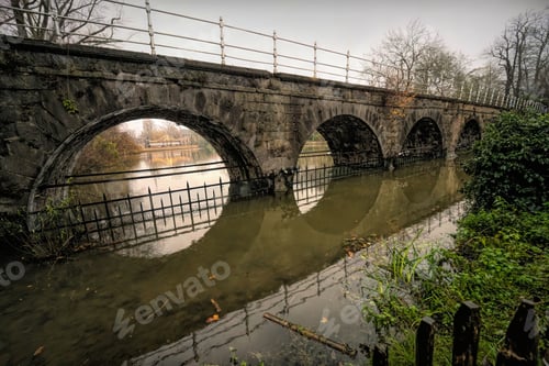 Preview: Arched pedestrian bridge and its reflection on a river in Bruges, Belgium