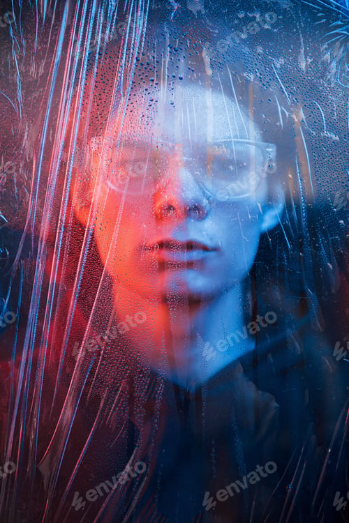 Preview: Studio shot in dark studio with neon light. Portrait of serious man behind the wet glass