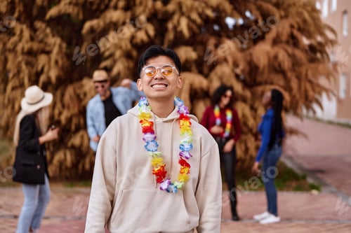 Preview: Asian man smiling while celebrating a party with friends outdoors.