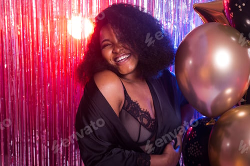 Preview: Young black woman looks happy while spend time in night club. Birthday party and nightlife concept