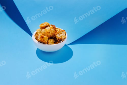 Preview: Golden crispy bread cubes in a white bowl against a blue