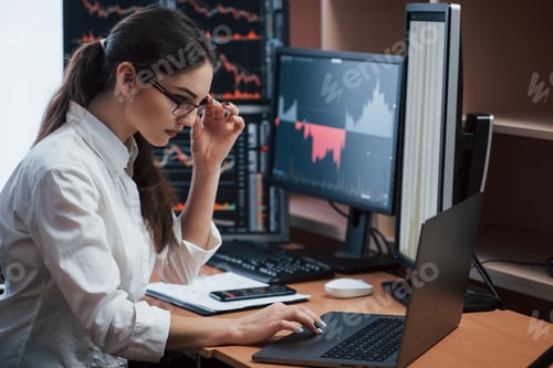 Preview: Woman working online in the office with multiple computer screens in index charts