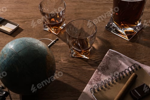 Preview: Glasses of brandy, cigar with globe and map on wooden table