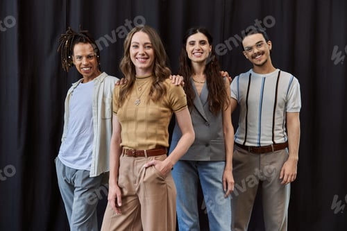 Preview: group photo of stylish multicultural business team smiling at camera near black drape in office