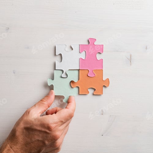 Preview: Top view of male hand joining four matching colorful puzzle pieces