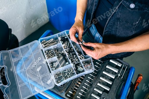 Preview: Mechanic's hands choosing screws from a tool box
