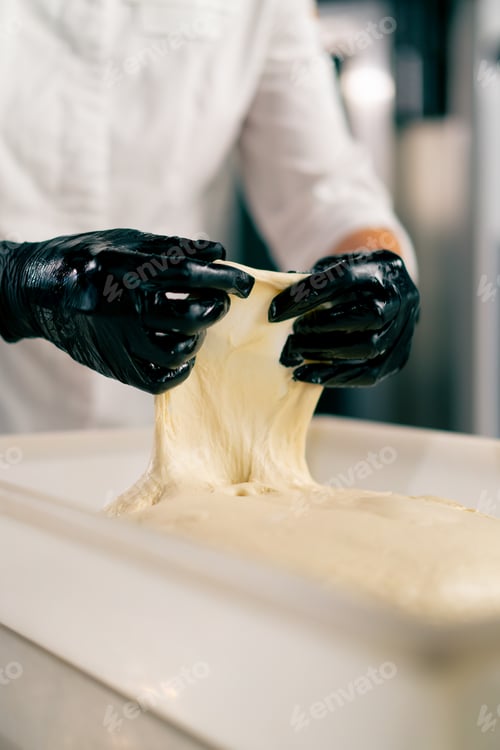 Preview: hands in gloves putting dough into a bread shape on a baking sheet for baking fresh pastries