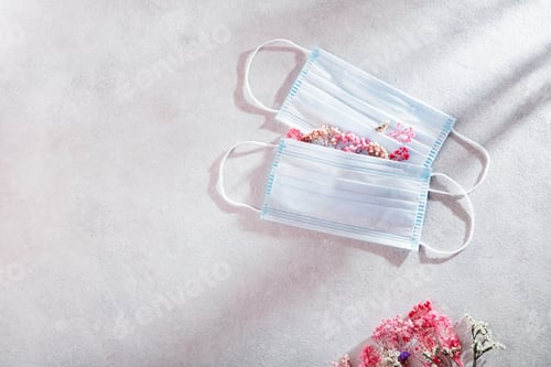 Preview: Two medical masks and flowers. The concept of seasonal allergies, flu and spring quarantine
