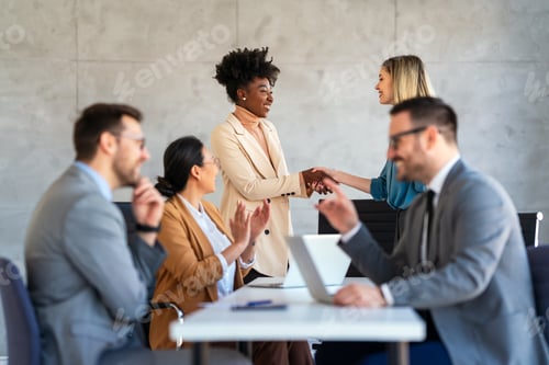 Preview: Happy businesspeople laughing while collaborating on a new project in an office.
