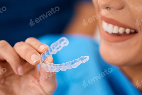 Preview: Close up of woman using invisible silicone dental aligner.