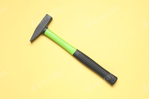 Preview: New hammer with rubber handle on yellow background, top view