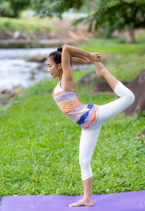 Preview: Young woman doing yoga exercises outdoors.