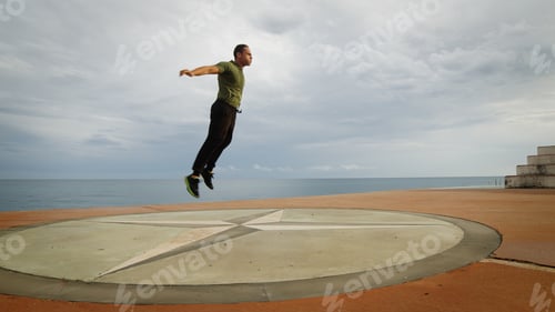 Preview: Young man is practicing fitness in park near the ocean