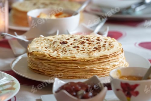 Preview: Closeup of a stack of appetizing Russian pancakes surrounded by toppings
