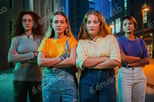 Preview: Portrait of a group of serious young women looking at camera together at night time. Proud feminine