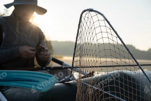 Preview: Net for pulling fish in inflatable boat, fisherman prepares for fishing against of lake in fog