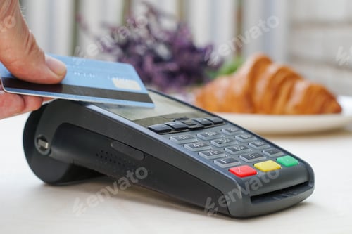 Preview: Close up young woman pays the purchase through the credit card at bakery. Bank payment terminal.