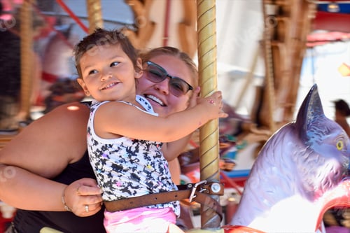 Preview: A mother and young daughter smiling on a moving carousel