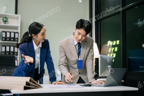 Preview: Two young Asian professionals engaged in teamwork and business discussions in office