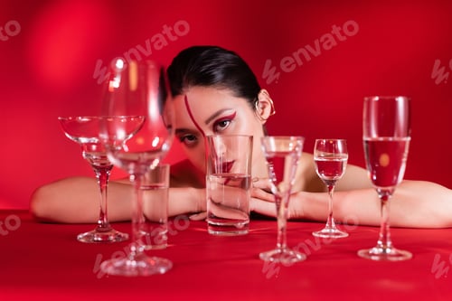 Preview: nude asian woman with artistic visage on face divided with line looking at camera near glasses on