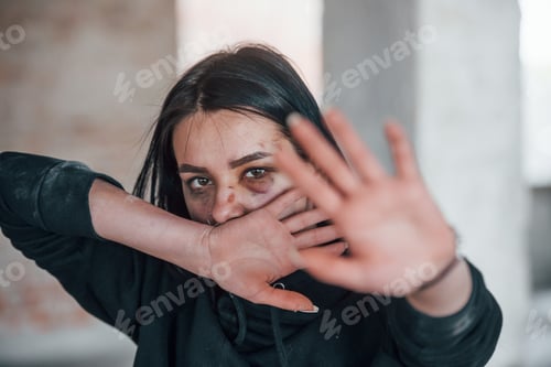 Preview: Portrait of beaten young woman with bruise under eye indoors in abandoned building