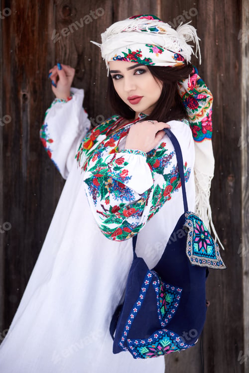 Preview: woman in white dress, sleeves embroidered, colorful kerchief and blue shoulder bag.