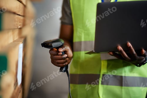 Preview: Close-up of black worker scanning labels while working at wood distribution warehouse.