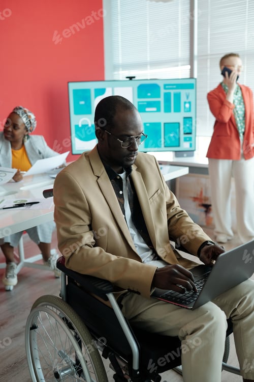 Preview: Man in Wheelchair Using Laptop in Office