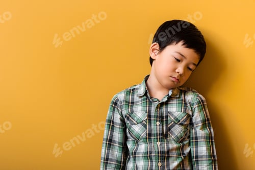 Preview: sad adorable asian boy standing on yellow