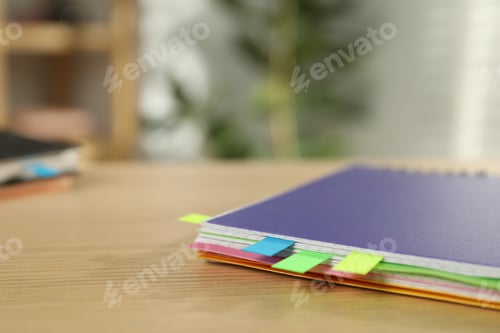 Preview: Notebook with colorful tabs on wooden table indoors, closeup. Space for text