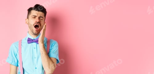 Preview: Image of tired guy in bow-tie yawning with opened mouth and closed eyes, standing sleepy, feeling