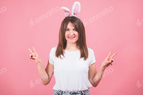Preview: Girl wearing bunny ears standing isolated on pink background